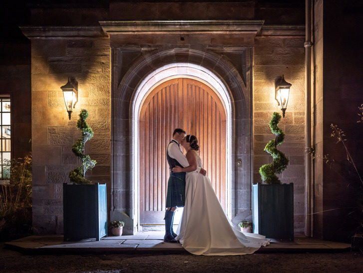 Bride and groom kiss outside main entrance